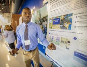 Innovative student presenting research poster at academic conference in a professional setting.