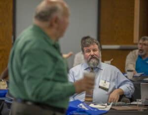 Engaged professional discussion at a conference or seminar with attendees in a classroom setting.