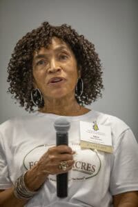 Empowered woman speaker at conference holding microphone, discussing community development.