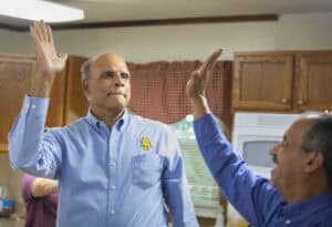 High-five between two men in a kitchen during a social gathering or celebration.