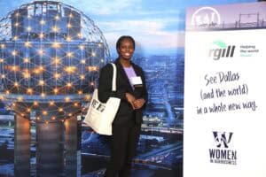 Innovative woman at CAES News event with Dallas skyline and globe display in background.