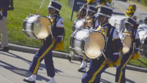 Bright marching band members playing drums during parade in uniform.