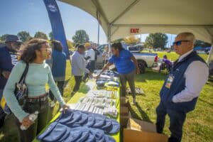 Community event with people browsing informational booths outdoors under a tent.