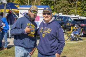 N.C. A&T Tigers alumni at outdoor event with tents and vehicles in background.