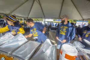 Freshly prepared food at a community event with volunteers serving under a large tent.