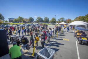 COVID-19 vaccination event with people waiting in line outdoors at a parking lot.