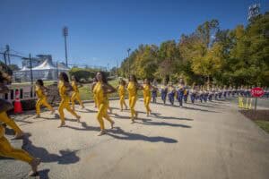Dance performance featuring dancers in yellow costumes outdoors during daytime.