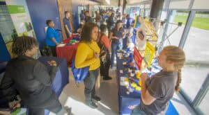 Students exploring educational exhibits at CAES News event in a bright indoor setting.