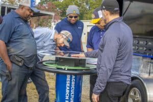 Innovative outdoor technology demonstration at CAES News event with diverse professionals.