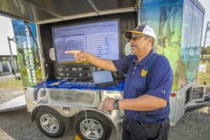 Emergency response professional explaining information on a mobile command unit at an outdoor event.