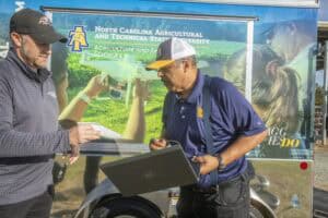 High school students and instructor discussing agricultural research outdoors at North Carolina Agri.