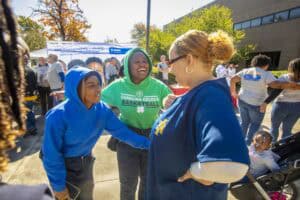 Community event with children and a woman engaging outdoors on a sunny day.