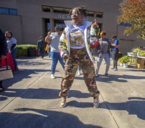Bright young girl dancing outdoors at a community event in front of B.C. Wildlife building, surround.