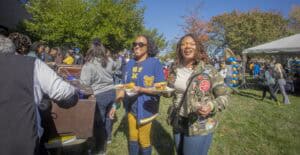 People enjoying outdoor event with food and socializing on a sunny day.