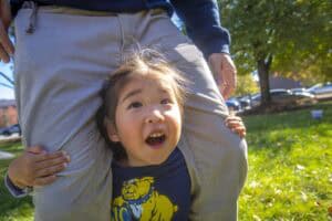 Happy child playing outdoors with adult in park on sunny day.