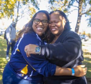 Happy women hugging outdoors during fall, smiling and showing friendship and joy.