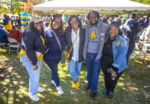 Celebrating alumni at CAES News outdoor event with diverse group of smiling graduates.