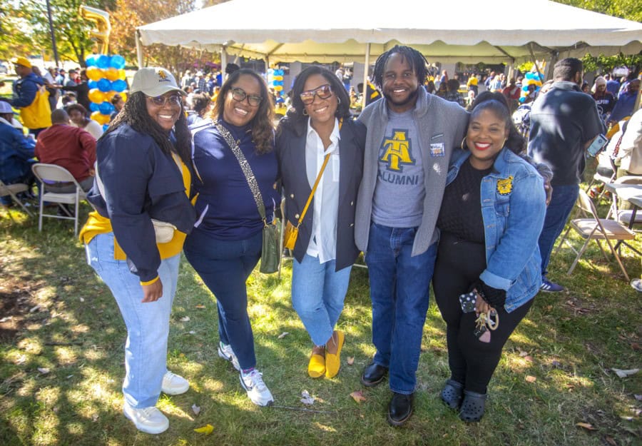 Celebrating alumni at CAES News outdoor event with diverse group of smiling graduates.