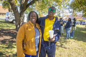 Happy community members enjoying outdoor event in park with trees and sunshine.