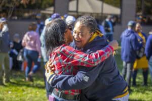 A woman and a girl hugging outdoors at a community event.