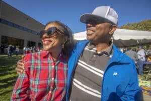 Enjoying outdoor event with smiling couple in casual attire on sunny day.