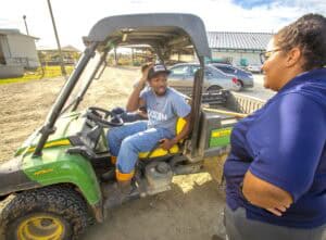 Young man smiling in a golf cart during an outdoor event in sunny weather.