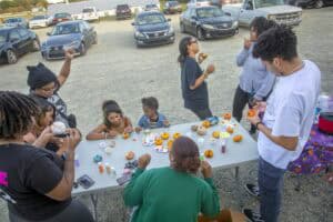 Pumpkin decorating activity outdoors with children and adults at a parking lot.