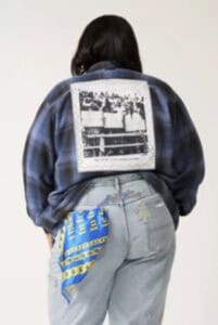 A woman with a denim jacket featuring a black-and-white photo on the back, wearing light jeans and a.