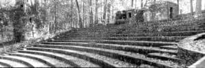 Ancient stone amphitheater surrounded by trees, showcasing historical architecture and natural scene.