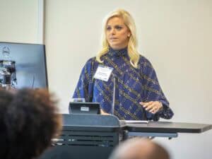 High-quality woman presenter at conference with computer and microphone in modern office setting.