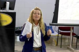 A woman giving a presentation in a classroom or conference room setting.