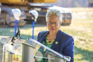 Accessible podium speaker at outdoor event with wood logs in background, emphasizing community engag.