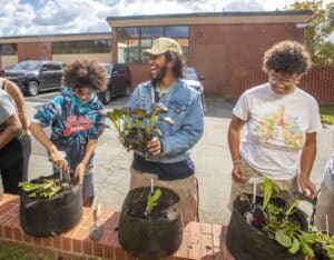 Planting community garden vegetables with diverse volunteers outdoors.