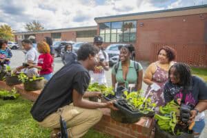 Community garden activity with diverse students and instructor engaging in planting outdoors at scho.