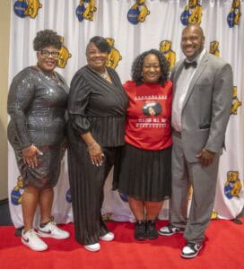 Celebrating diversity and unity at CAES News event with smiling professionals in stylish attire.