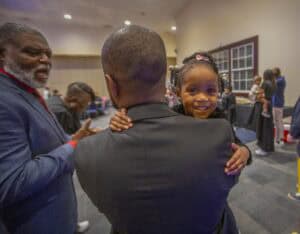 Celebrate with a young girl hugging a man at a community event, showcasing joy and togetherness.