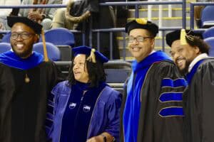 Graduates celebrating at a university graduation ceremony in academic regalia.