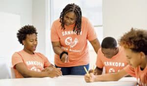 Sankofa STEM Academy teacher engaging with diverse students in classroom.
