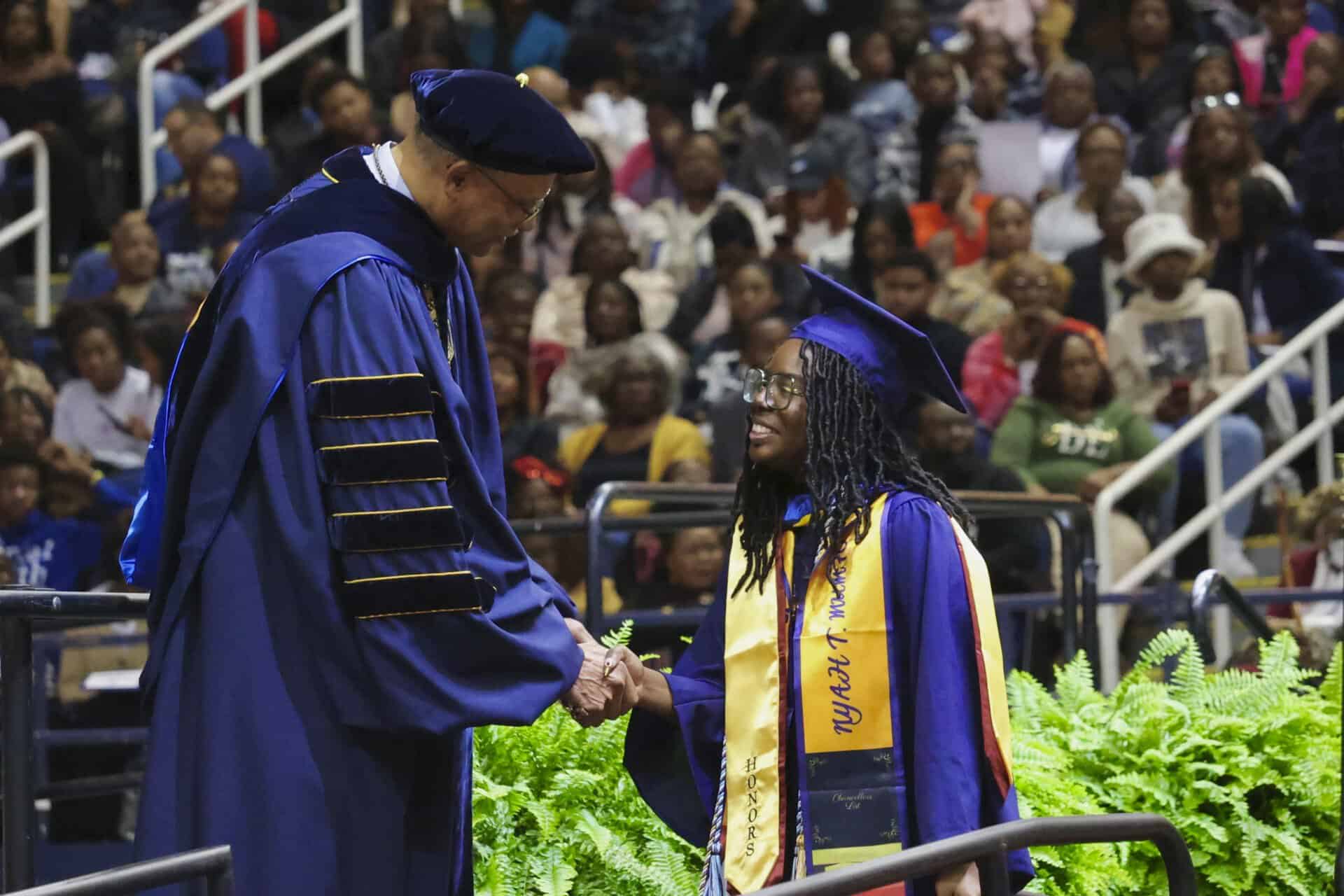Graduation ceremony with graduate receiving diploma from university official.