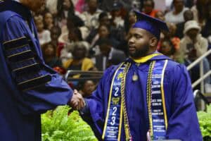 Graduation graduate shaking hands during ceremony at CAES News event.