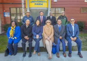 Diverse group of professionals posing outside University Farm building for a photo.