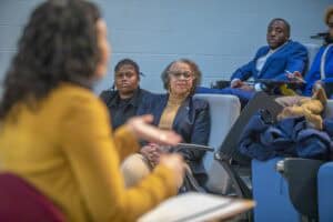 A group of people engaged in a discussion, with one woman speaking and others listening attentively.