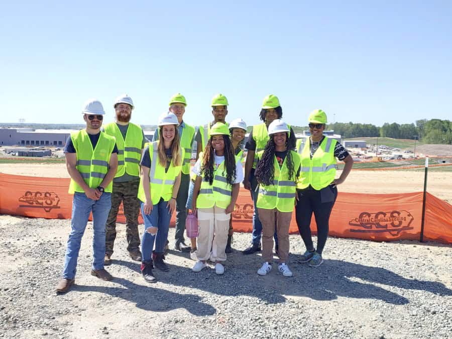 Construction team wearing safety vests and helmets at a building site.