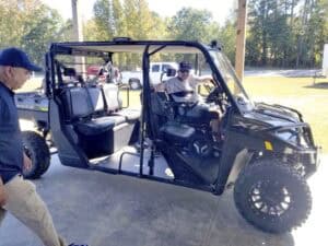 Off-road utility vehicle with four passengers outdoors in a park setting.