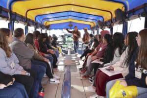 Group of people attending a guided tour on a boat with a colorful canopy.