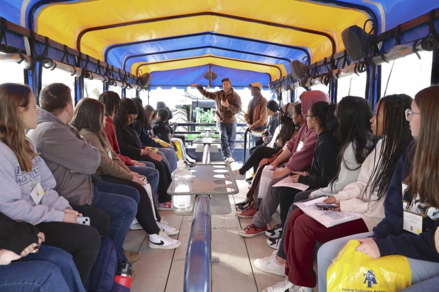 Group of people attending a guided tour on a boat with a colorful canopy.