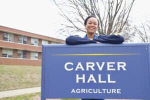Student smiling at Carver Hall Agriculture building on campus.