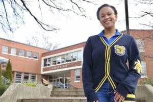 Bright smiling student standing outside Carver Hall at CAES News campus.