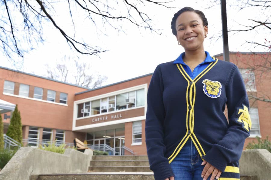 Bright smiling student standing outside Carver Hall at CAES News campus.