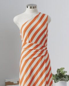 Orange and white striped one-shoulder dress displayed on a mannequin.